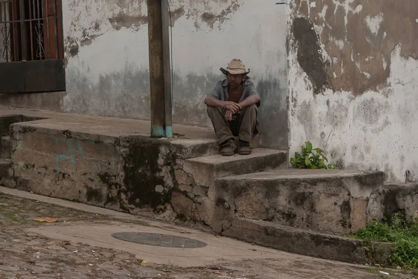 Suchitoto, El Salvador. 03-18-2019. Suchitoto 'da uzun bir çalışma gününden sonra yaşlı işçi kaldırımda oturuyor..