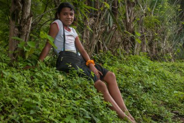 Suchitoto, El Salvador. 03-21-2019. Suchitoto şehrinin kırsal kesiminde çimlerin üzerinde oturan güzel bir genç kızın portresi..