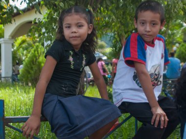 Suchitoto, El Salvador. 03-21-2019. Suchitoto 'da pazar günü bir bankta oturan bir kız ve erkek çocuğunun portresi..