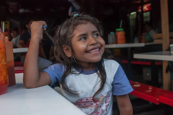 Suchitoto, El Salvador. 03-21-2019. Suchitoto 'daki pazar günü annesine yardım eden gülümseyen bir kızın portresi..