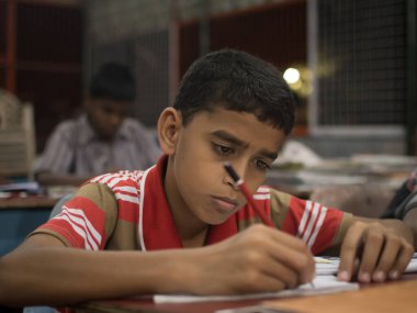 Varanasi, Hindistan. 10-16-2019. Okulda yemek yemeden önce ödevini yapan bir çocuğun portresi..