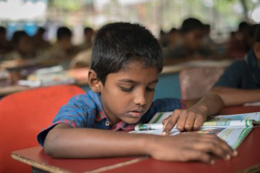 Varanasi, Hindistan. 10-14-2019. Bir çocuk ödevini yaparken yatılı okulda ders kitabını okuyor..