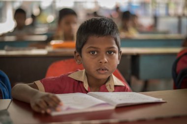 Varanasi, Hindistan. 10-14-2019. Okulda ders sırasında bankta oturan bir çocuğun portresi..