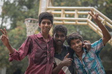 Varanasi, Hindistan. 10-14-2019. Öğleden sonra okulda basketbol oynadıktan sonra kameraya gülümseyen üç ergene yakın çekim..