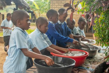 Dodoma, Tanzanya. 08-18-2019. Çocuklar öğle yemeği için toplanıyor ve okul bittikten sonra Tanzanya 'da kirli bulaşıkları yıkıyorlar..