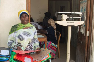 Dodoma, Tanzanya. 10-10-2018. Hastanede çalışan siyahi bir Müslüman kadın, Tanzanya 'da bir sonraki hastasının yardım almasını beklerken evrak işlerini organize ediyor..