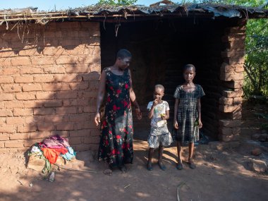 Mzuzu, Malawi. 30-05-2018. Malawi 'deki kırsal bir köyde iki kızıyla birlikte kameraya gülümseyen mutlu afro-torun anne..