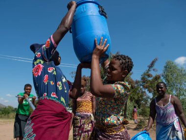 Mzuzu, Malawi. 30-05-2018. Topluluktan anne ve çocuklar, Malawi 'de içmek ve yemek pişirmek için içilebilir su getirmek üzere toplandılar..