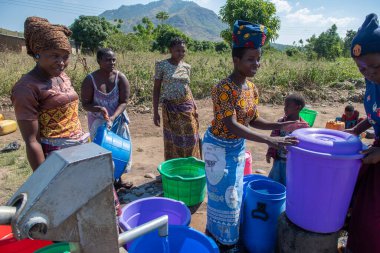 Mzuzu, Malawi. 30-05-2018. Topluluktan anne ve çocuklar, Malawi 'de içmek ve yemek pişirmek için içilebilir su getirmek üzere toplandılar..