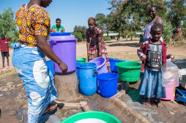 Mzuzu, Malawi. 30-05-2018. Topluluktan anne ve çocuklar, Malawi 'de içmek ve yemek pişirmek için içilebilir su getirmek üzere toplandılar..