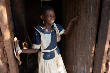 Mzuzu, Malawi. 30-05-2018. Okul üniformalı siyahi bir kızın portresi. Okuldan eve döndükten sonra Malavi 'deki kırsal bir köyde evinin önünde gülümsüyor..