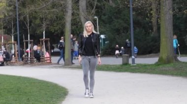 Prag, Çek Cumhuriyeti. 04-16-2021. Güzel, çekici, sarışın genç bir kadın güneşli bir bahar gününde Prag şehrindeki Park Stromovka 'da yürüyor.