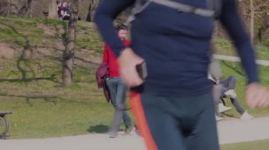 Prag, Çek Cumhuriyeti. 04-16-2021. Prag şehrinde güneşli bir bahar gününde beyaz bir genç kadın ve genç bir afro-erkek Park Stromovka 'da yürüyor ve konuşuyorlar..