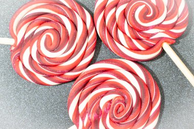 Noel şekeri, gri bir arka planda kırmızı ve beyaz girdaplar. Noel örtüsü, düzlük.