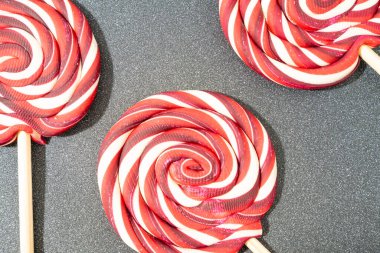 Noel şekeri, gri bir arka planda kırmızı ve beyaz girdaplar. Noel örtüsü, düzlük.