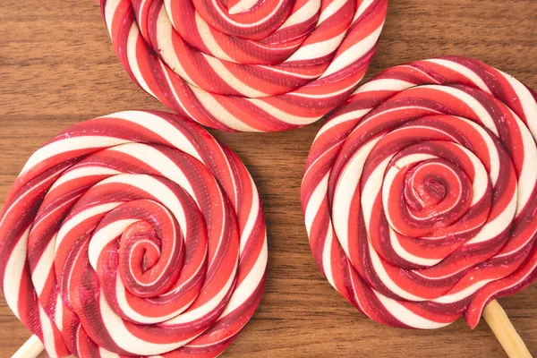 Ahşap arka planda kırmızı ve beyaz kıvrımlı Noel lolipopları. Noel arkaplanı.