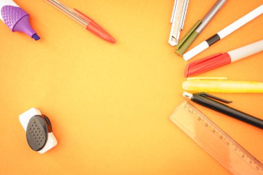 Turuncu arka planda farklı bir okul ya da ofis malzemeleri var. Düz Yatay.