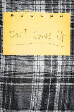 El yazısıyla yazılmış bir not. Vazgeçme. Pozitif notlar. tekstil arka planında.