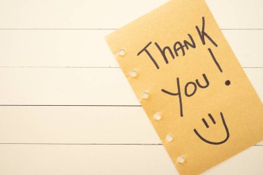 Yapışkan bir nota yazılmış bir teşekkür. Beyaz ahşap arka planda.