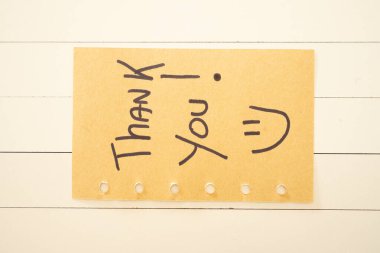 Yapışkan bir nota yazılmış bir teşekkür. Beyaz ahşap arka planda.