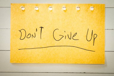 El yazısıyla yazılmış bir not. Vazgeçme. Pozitif notlar. beyaz ahşap bir arka planda.