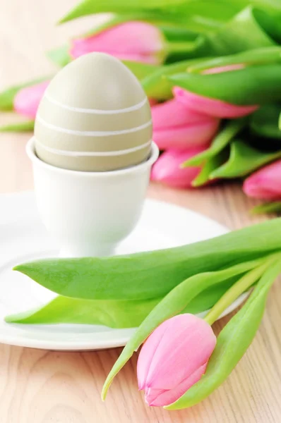 Easter egg in cup with bunch of tulips around — Stock Photo, Image