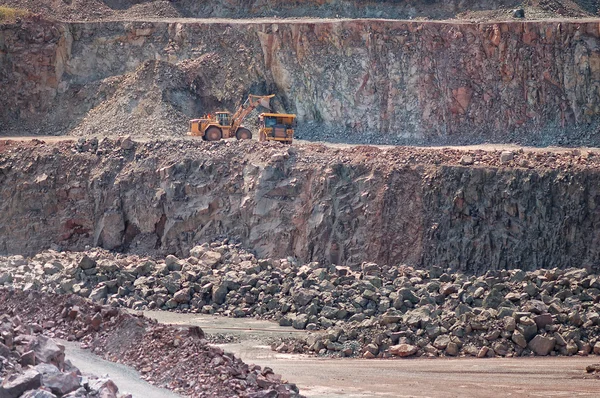 Excavadora cargando un camión volquete con rocas en una mina de cantera . — Foto de Stock