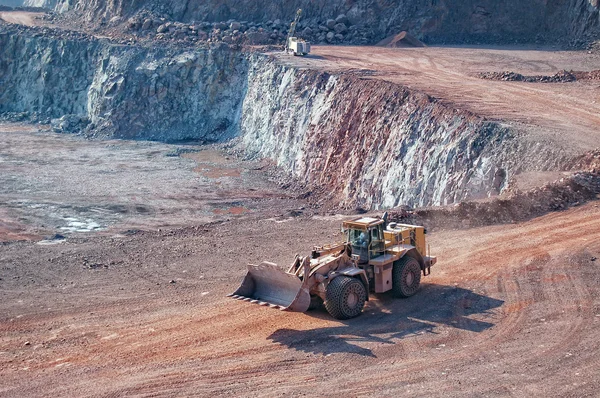 Excavadora conduciendo a través de la cantera. taladro en el fondo — Foto de Stock