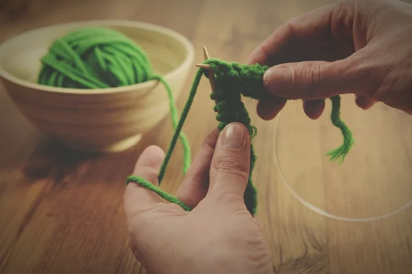 Вязание с зеленой шерстью на деревянном столе — стоковое фото