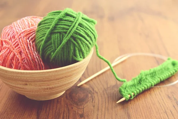 Вязание с зеленой шерстью на деревянном столе — стоковое фото