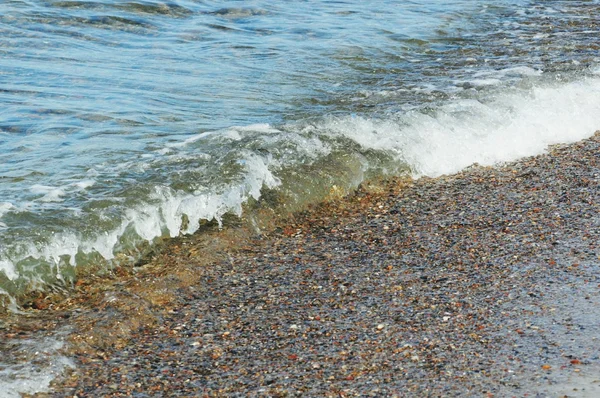 Seixos na praia de porto mais escuro nas ondas . — Fotografia de Stock