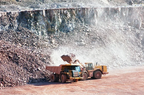 Eath mover loading stones on a dumper truck — Stock Photo, Image