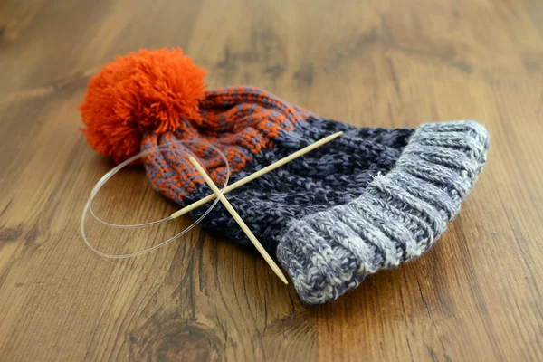 Knitting wolly hat. finished hat on table. with needles — Stock Photo, Image