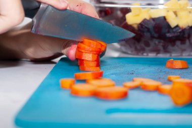 Sebze ve havuç keser. Genç kız annesine yardım ediyor..