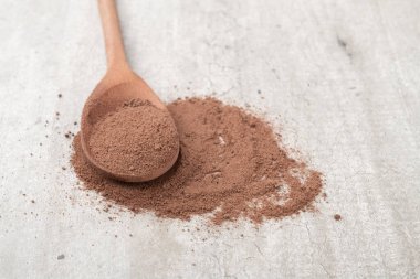 Kakao tozu, ahşap bir kaşıkta, kırsal arka planda..