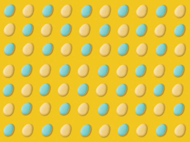 Sarı arka planda mavi ve sarı paskalya yumurtası kurabiyeleri.