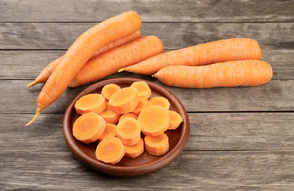 Carrots and slices on a plate over wooden table.