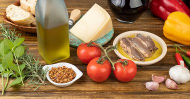 Sebze, zeytinyağı, ekmek, peynir, balık, şarap ve sebzeler ahşap masanın üzerinde. Akdeniz yemekleri.