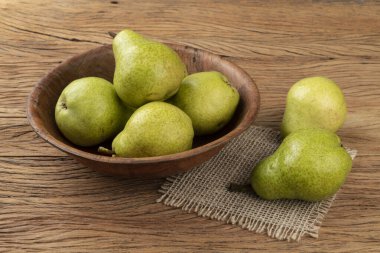 Ahşap bir masanın üzerinde yeşil armutlar.