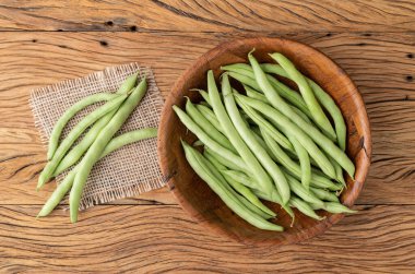 Bir grup yeşil fasulye kabı ahşap masanın üzerinde bir kasede..