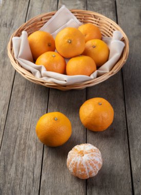 Mini tangerines in a basket over wooden table.