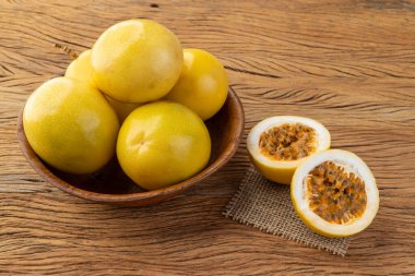 Ahşap bir masanın üzerinde kesilmiş meyvelerle dolu bir kasede tutku meyveleri..