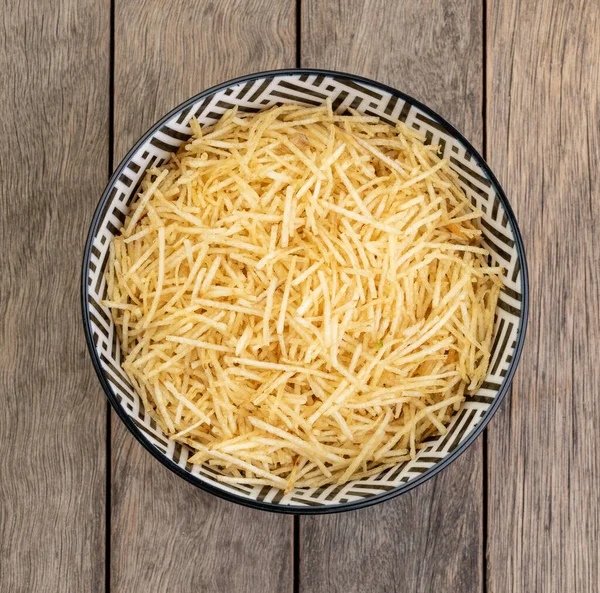 Potato straw or shoestring potato in a bowl over wooden table.