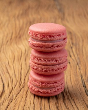 Tahta masanın üzerine istiflenmiş üç çilekli kurabiye..