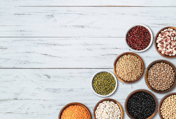 Assorted beans over wooden table with copy space.