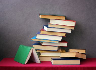 Bir kitap bir kırmızı masa örtüsü ile masada yığını.