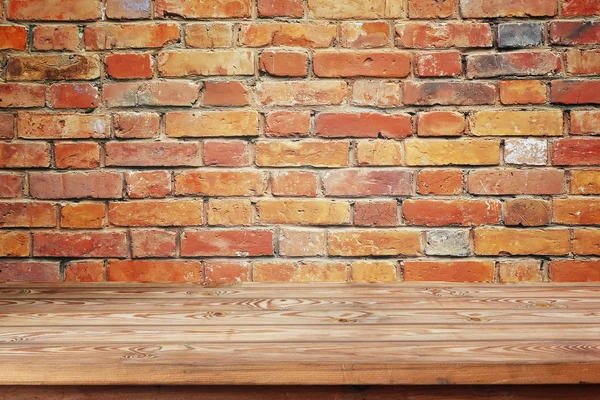 Mesa de madeira vazia contra uma parede de tijolo — Fotografia de Stock