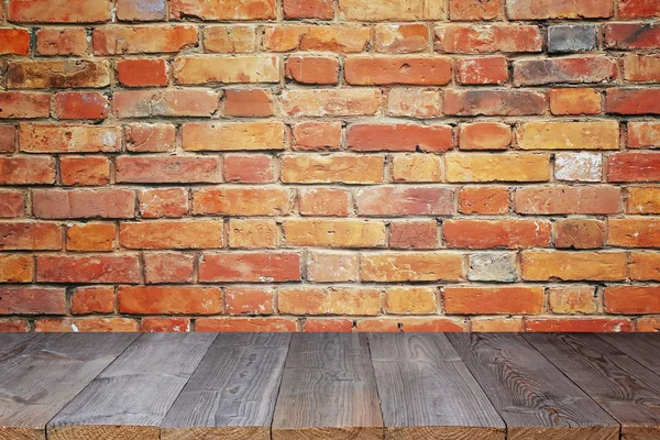 Mesa de madeira vazia contra uma parede de tijolo — Fotografia de Stock