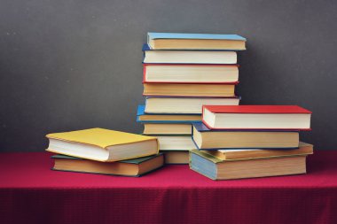 Bir kitap bir kırmızı masa örtüsü ile masada yığını.