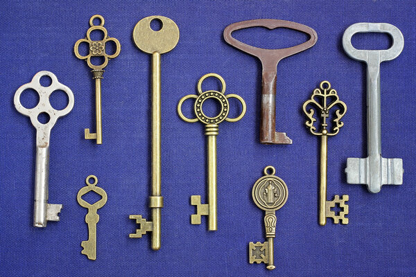 Metal keys from different locks on a blue background.